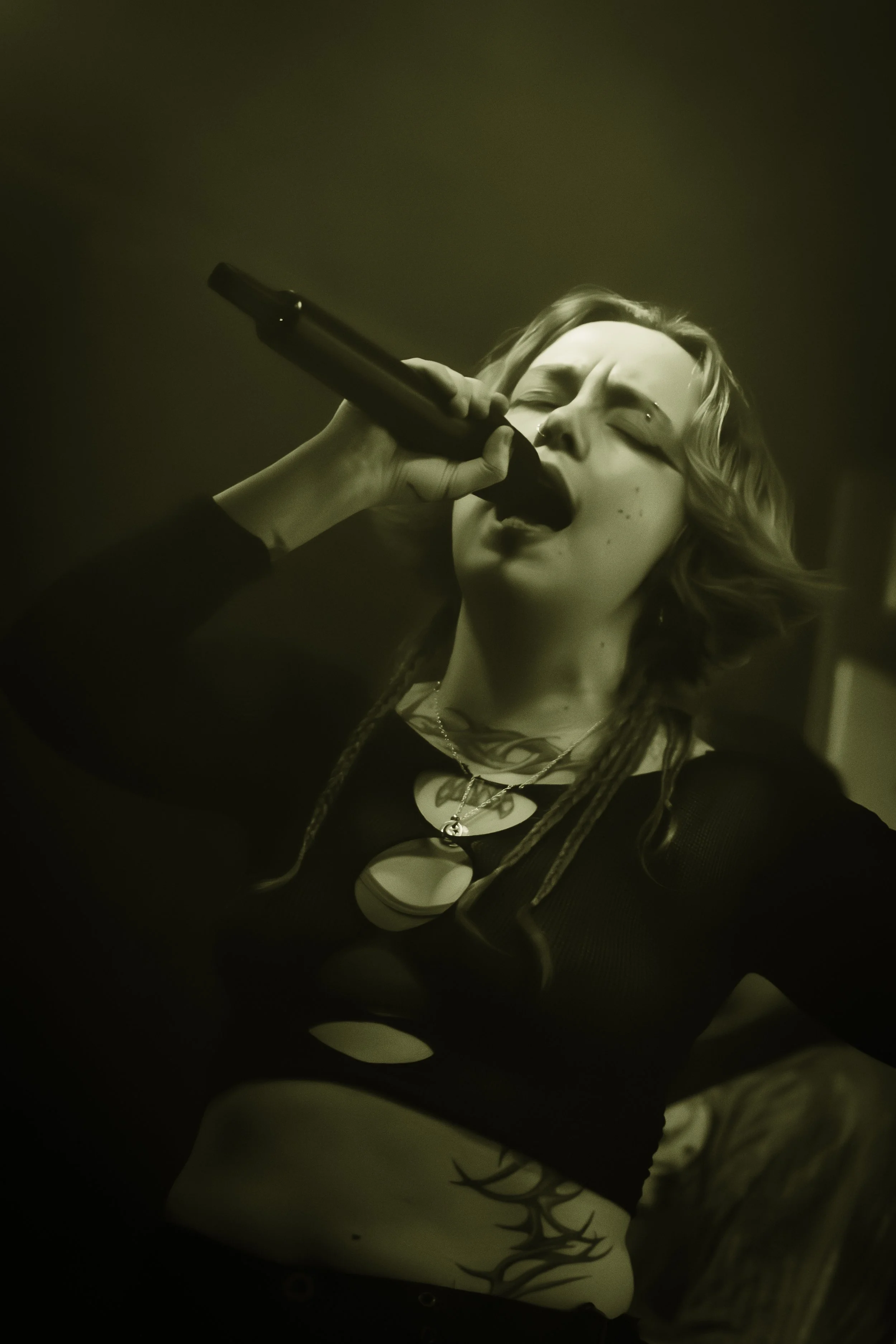 A woman with curly hair singing into a microphone.