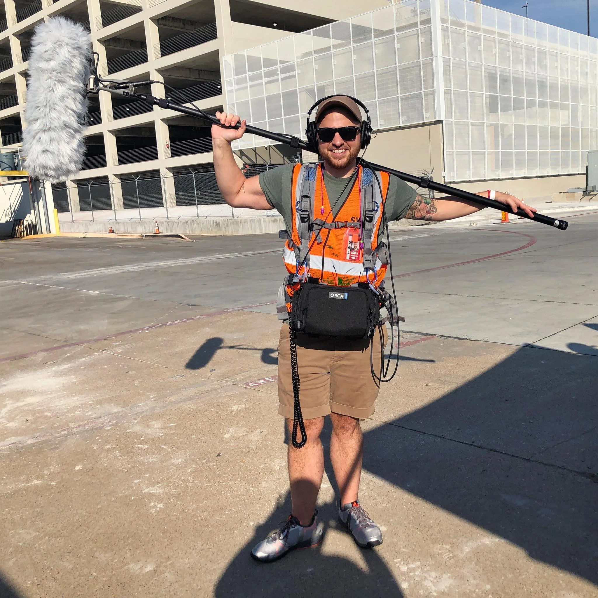 Ethan Avanzino on a film production set on an airport tarmac holding a boom mic
