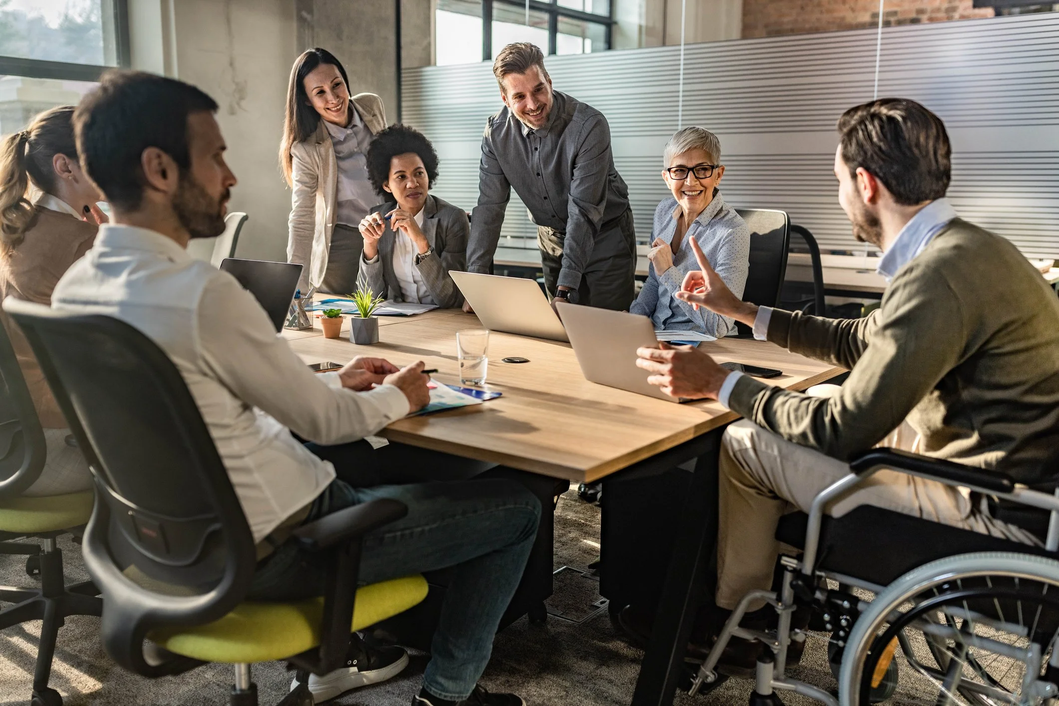 Diverse team of professionals collaborating around a conference table led by a person in a wheelchair