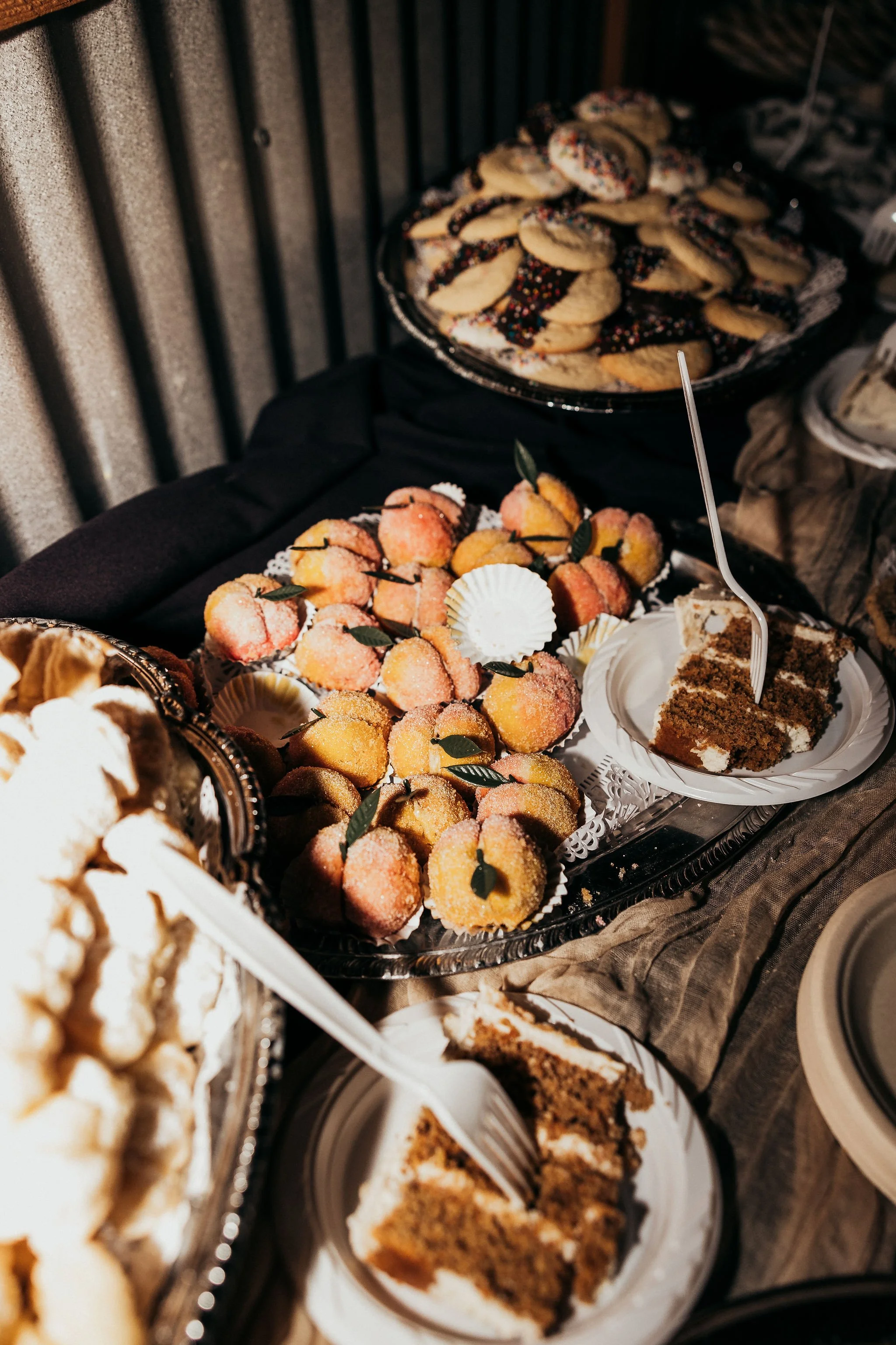 Assorted desserts including cookies with sprinkles, fruit-topped treats, and slices of cake on a buffet table.