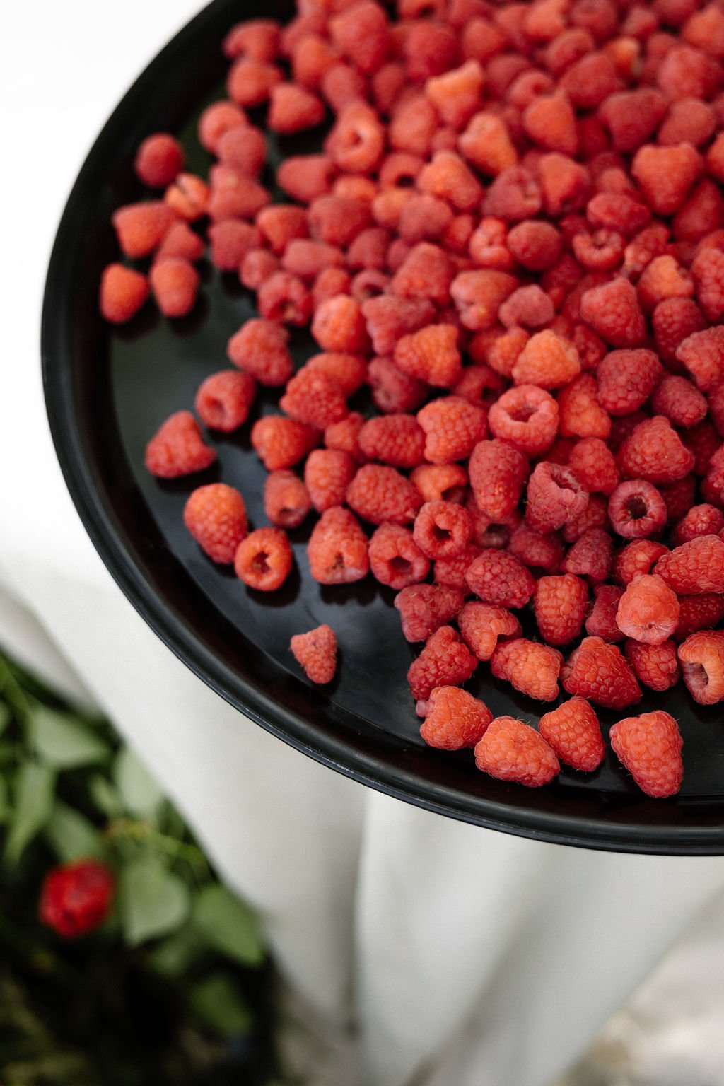 A black tray filled with frozen raspberries.