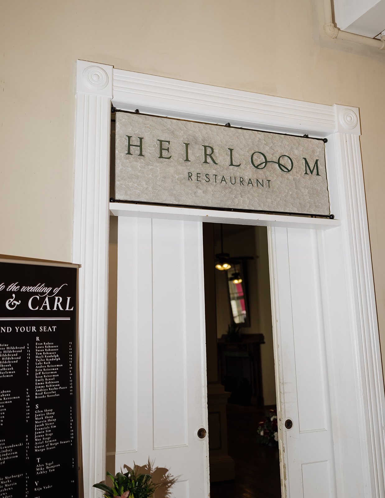 Sign reading 'Heirloom Restaurant' above white french doors at restaurant entrance.