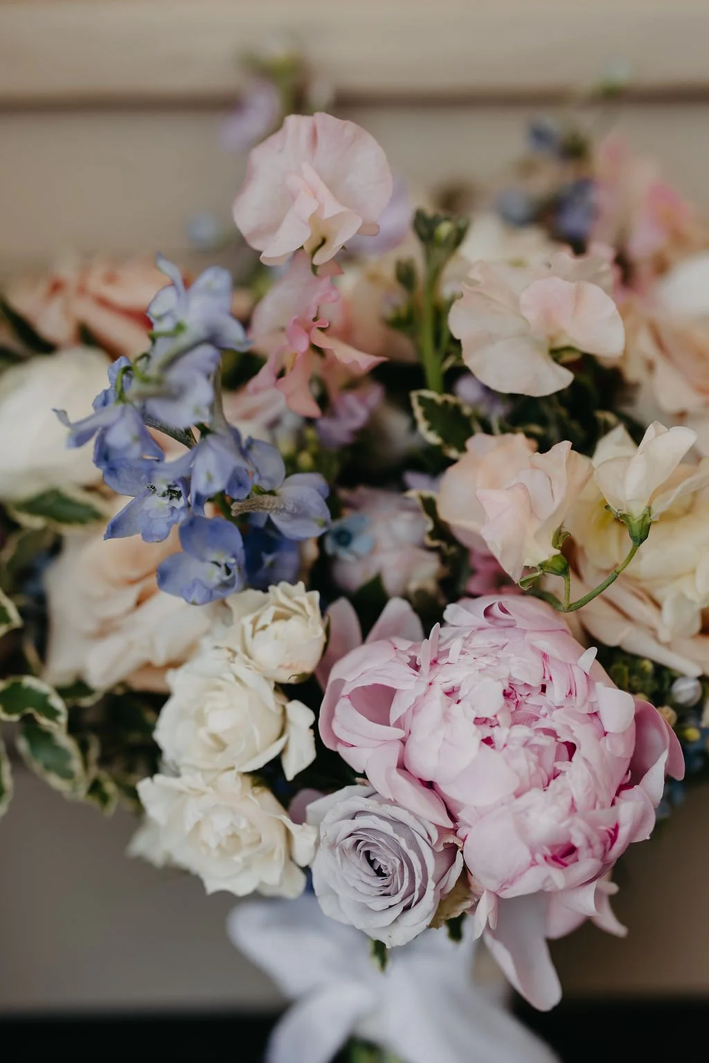 Close-up of a colorful bouquet of various pastel-colored flowers including pink, white, purple, and cream flowers, some with green variegated leaves.