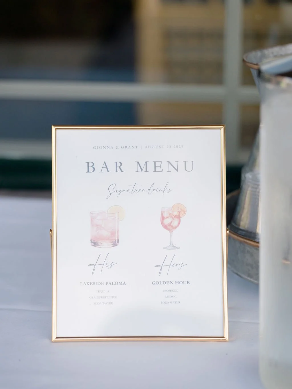 A framed wedding bar menu featuring signature drinks for Gionna and Grant on August 23, 2023, displaying two cocktails with ingredients listed.