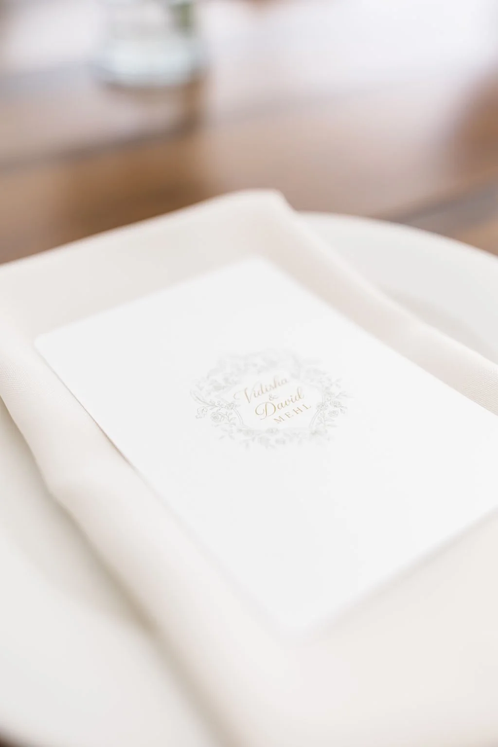 Wedding invitation with a floral design and the names Nadisha and Davi in gold lettering.