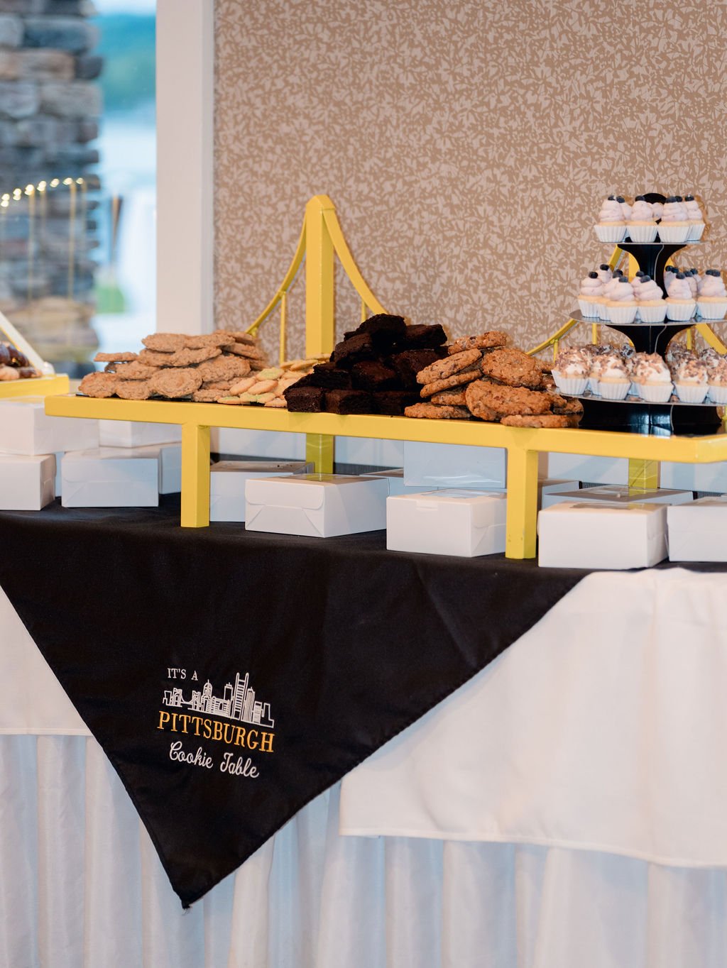 Cookies and cupcakes on a yellow dessert stand at a Pittsburgh cookie table event.