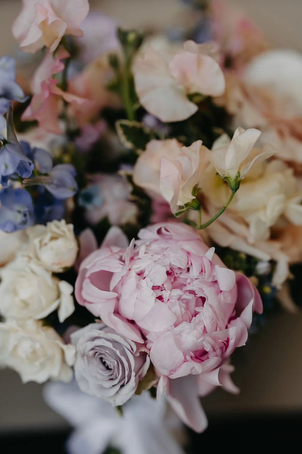 Close-up of a bouquet of various pastel-colored flowers, including pink, white, cream, and lavender blooms.