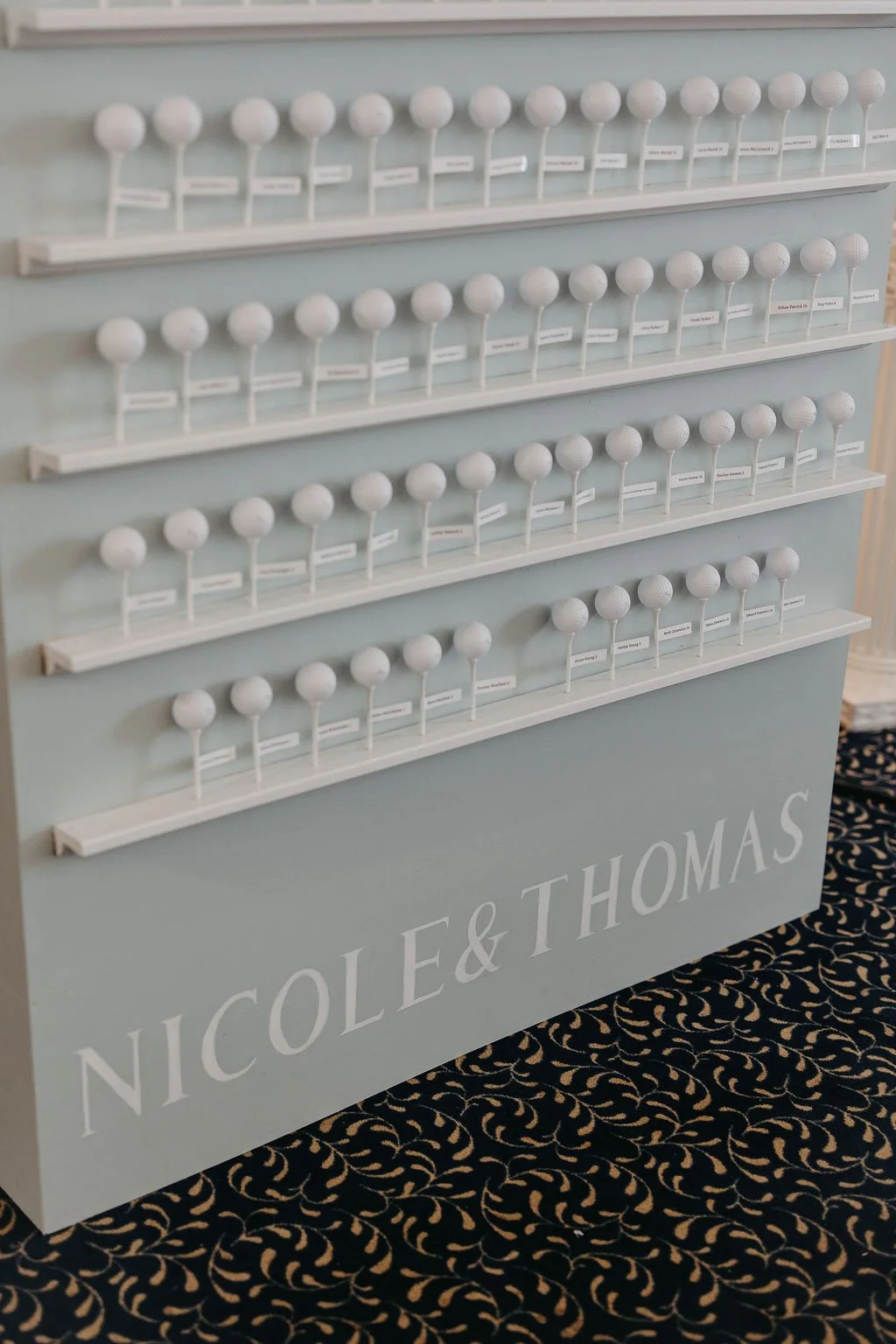 Display of white golf balls on shelves with labels, at a Nicole & Thomas event or shop.