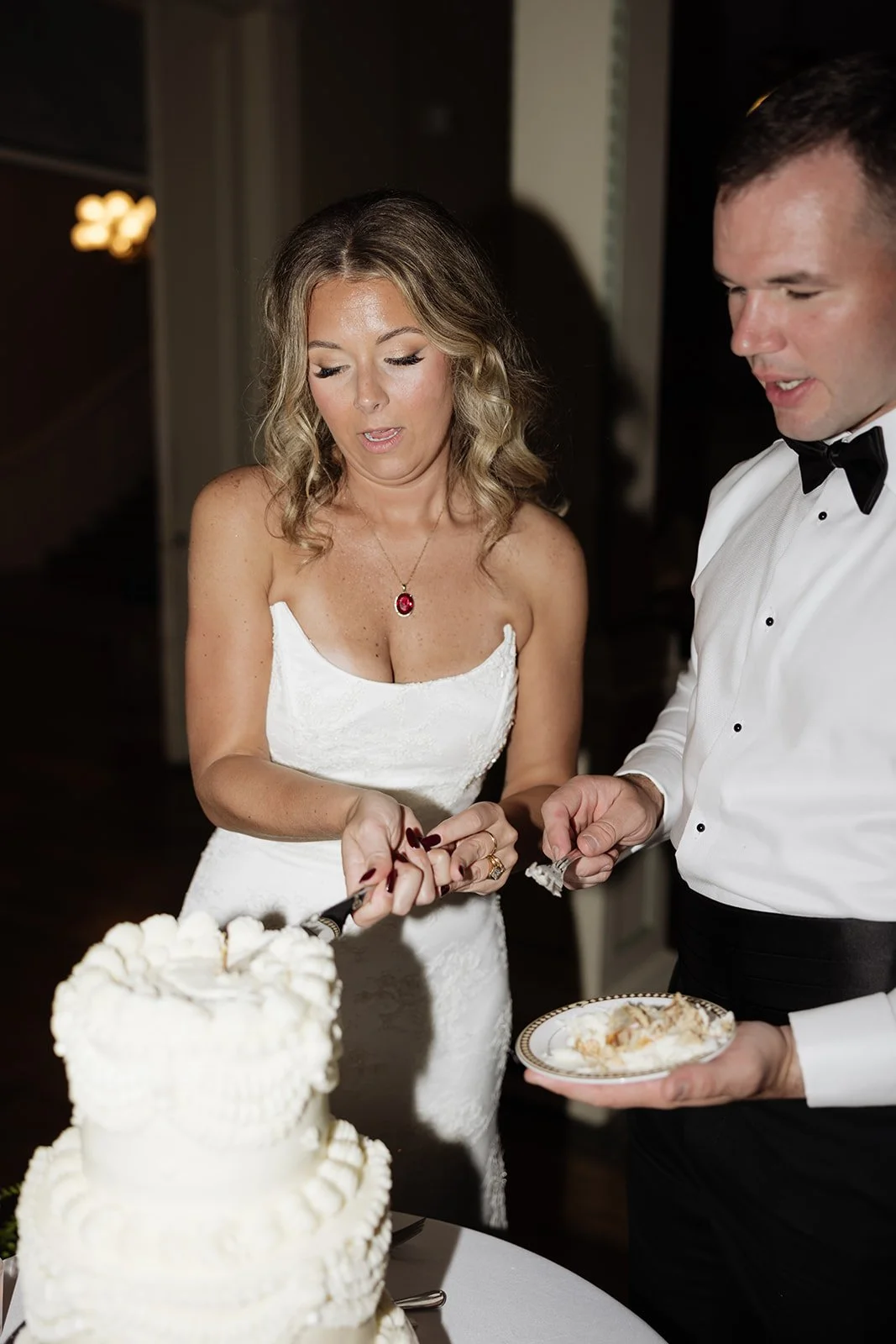 A bride and groom cutting a wedding cake together during their wedding reception.