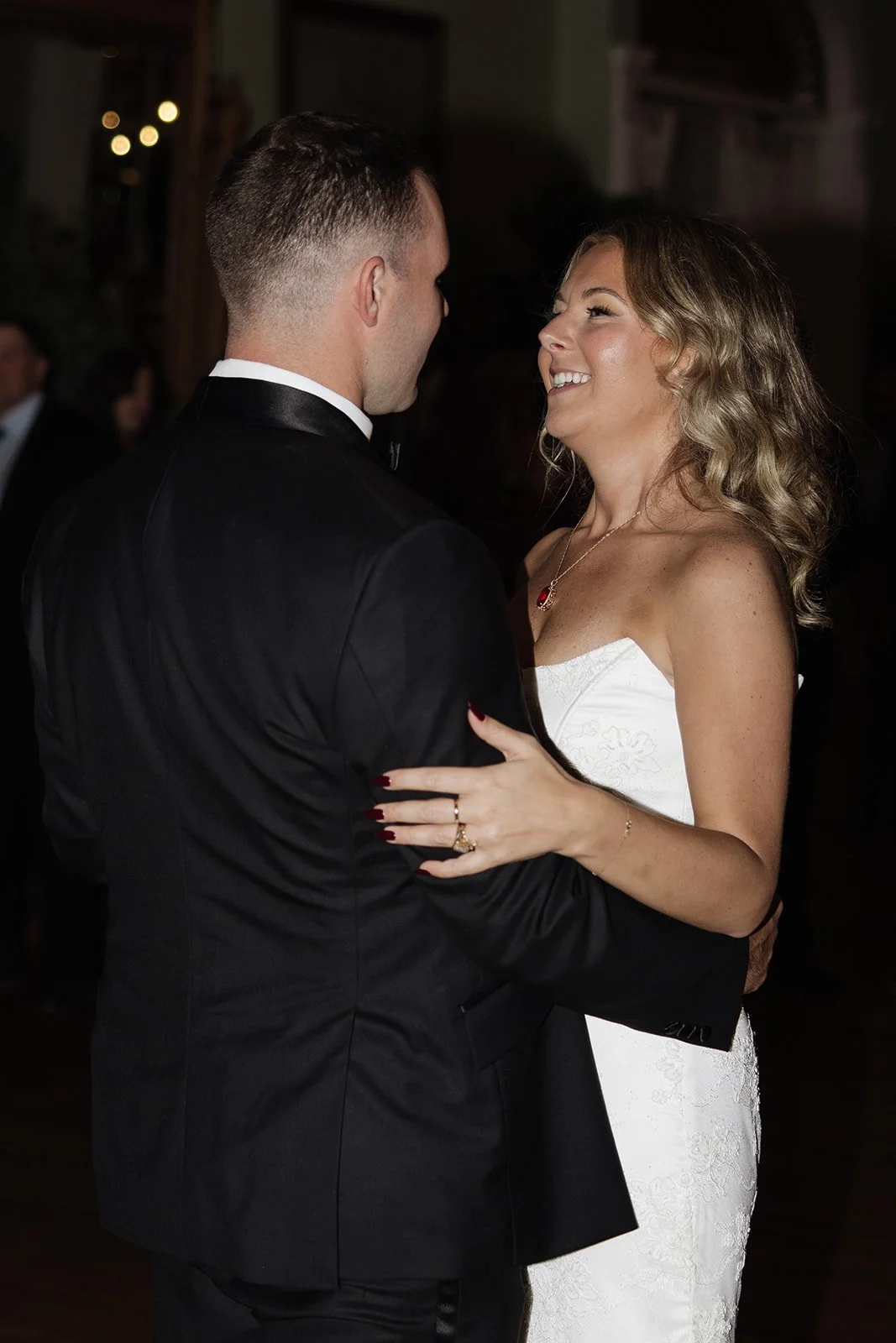 A bride and groom dance during their wedding reception, smiling at each other in an elegant indoor setting.