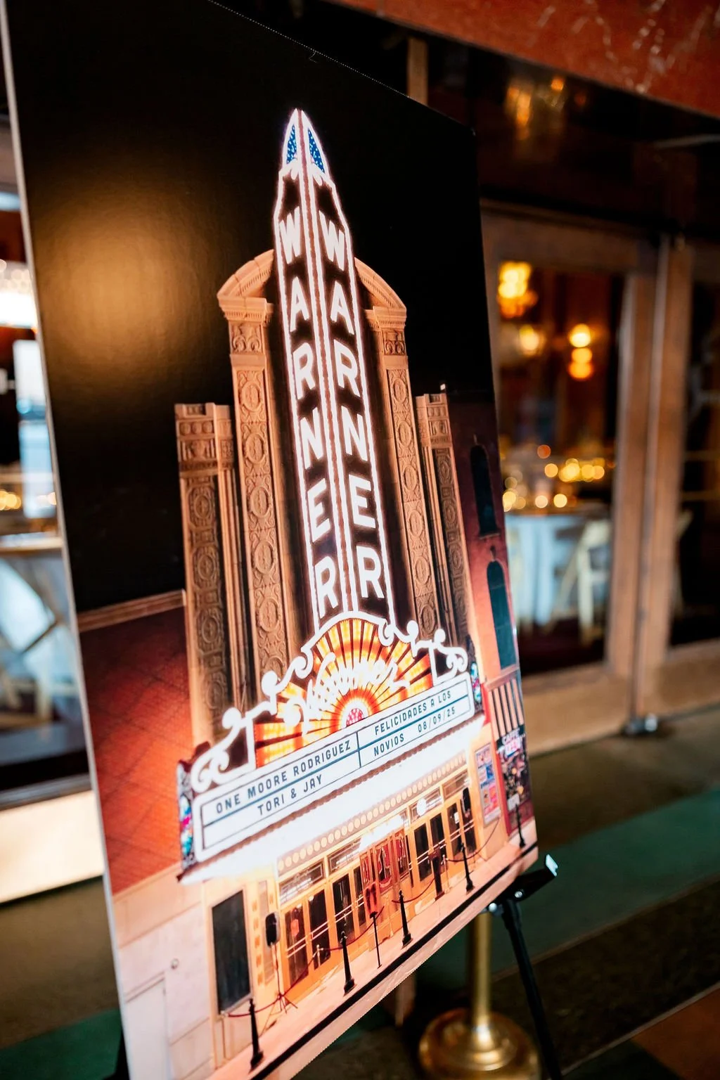 Photo of a wedding announcement poster featuring the Hollywood Theatre's iconic neon sign at night, announcing the marriage of Tori and Jay on September 8, 2025.