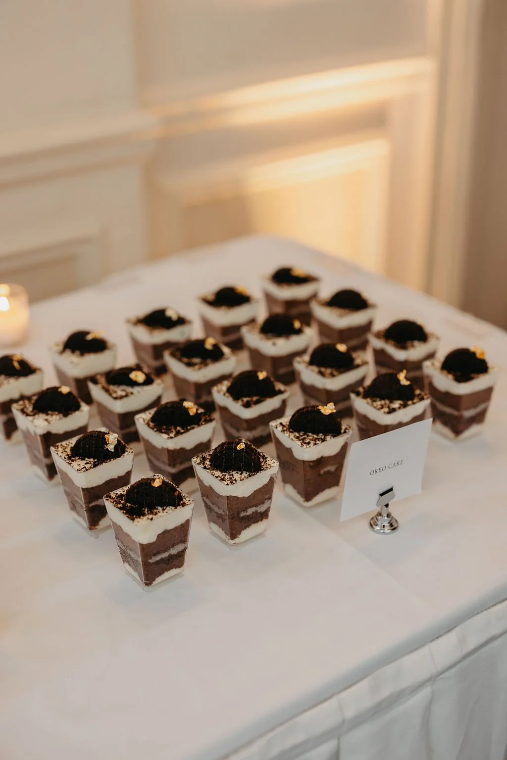 A tray of small square Oreo-themed desserts with white frosting and Oreo cookie toppings, labeled 'Oreo Cake'.