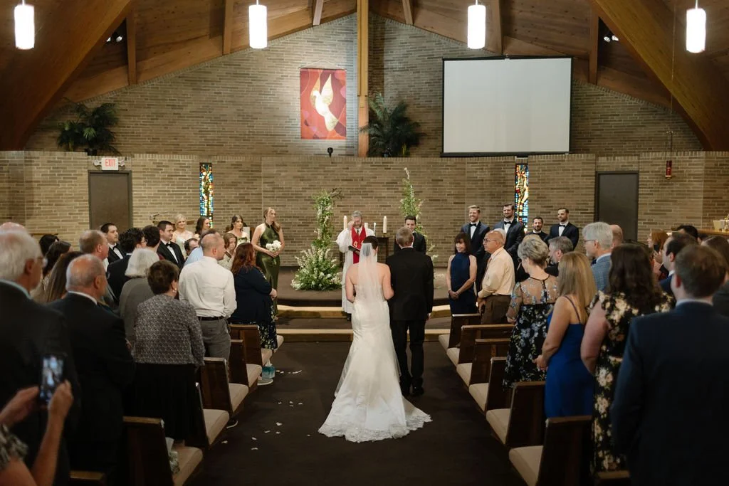 A bride and groom walking down the aisle during a wedding ceremony inside a church with guests watching.