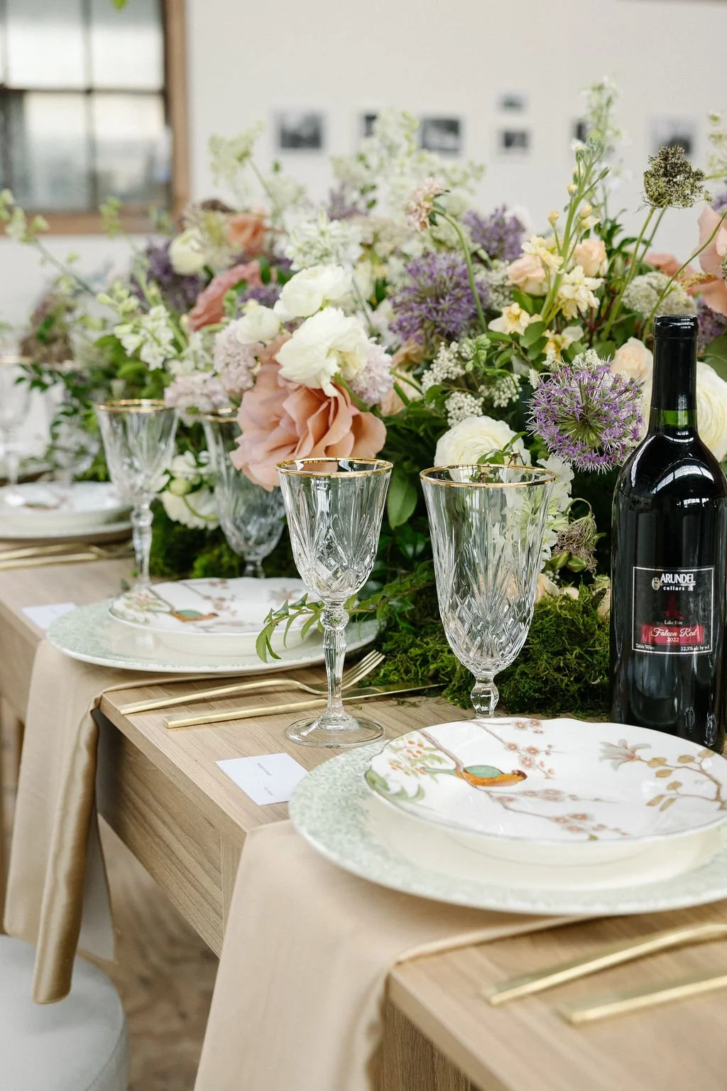 A beautifully set dining table with floral centerpieces, crystal glasses, and patterned plates.