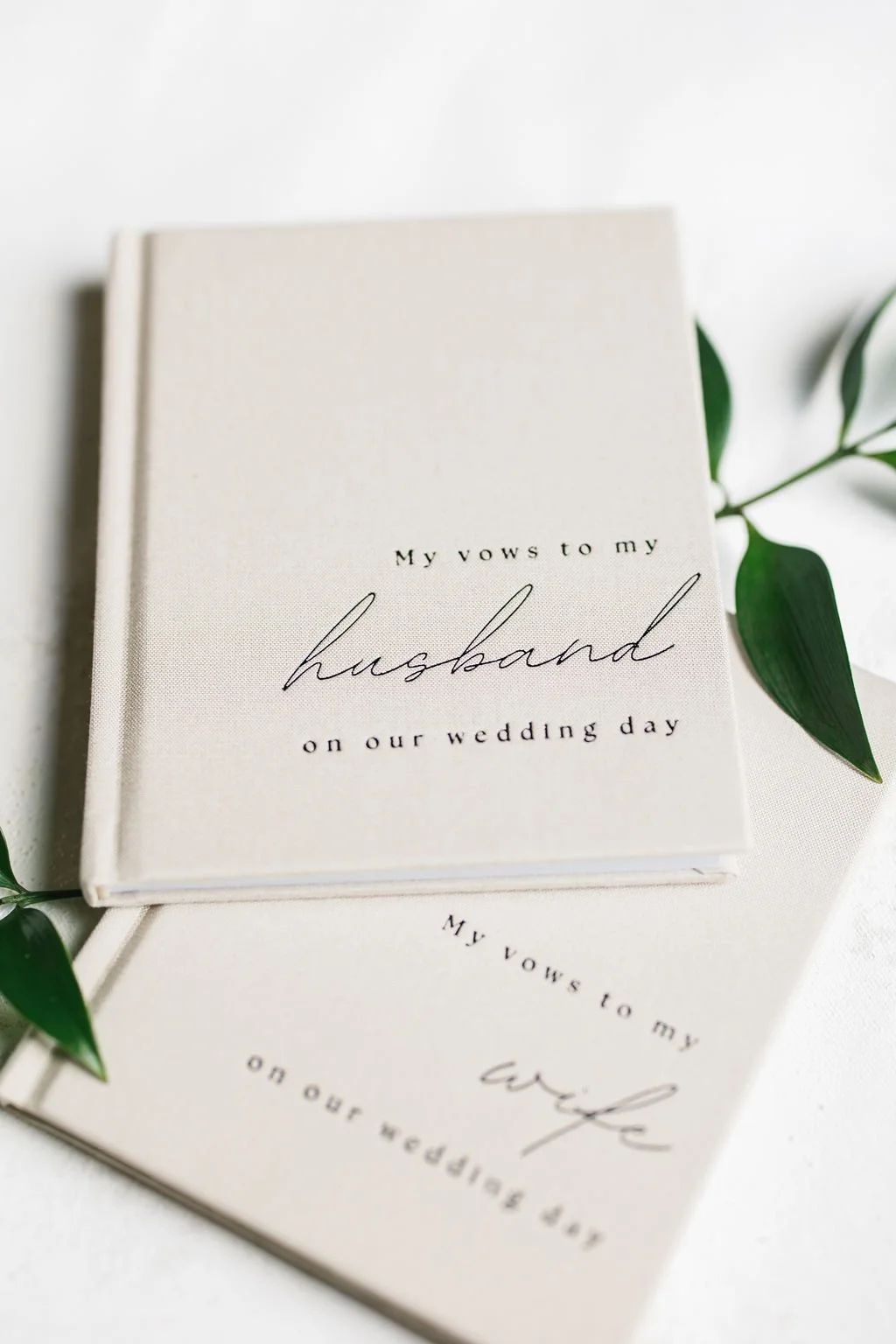 Wedding vow book with text 'My vows to my husband on our wedding day' accompanied by green leaves.