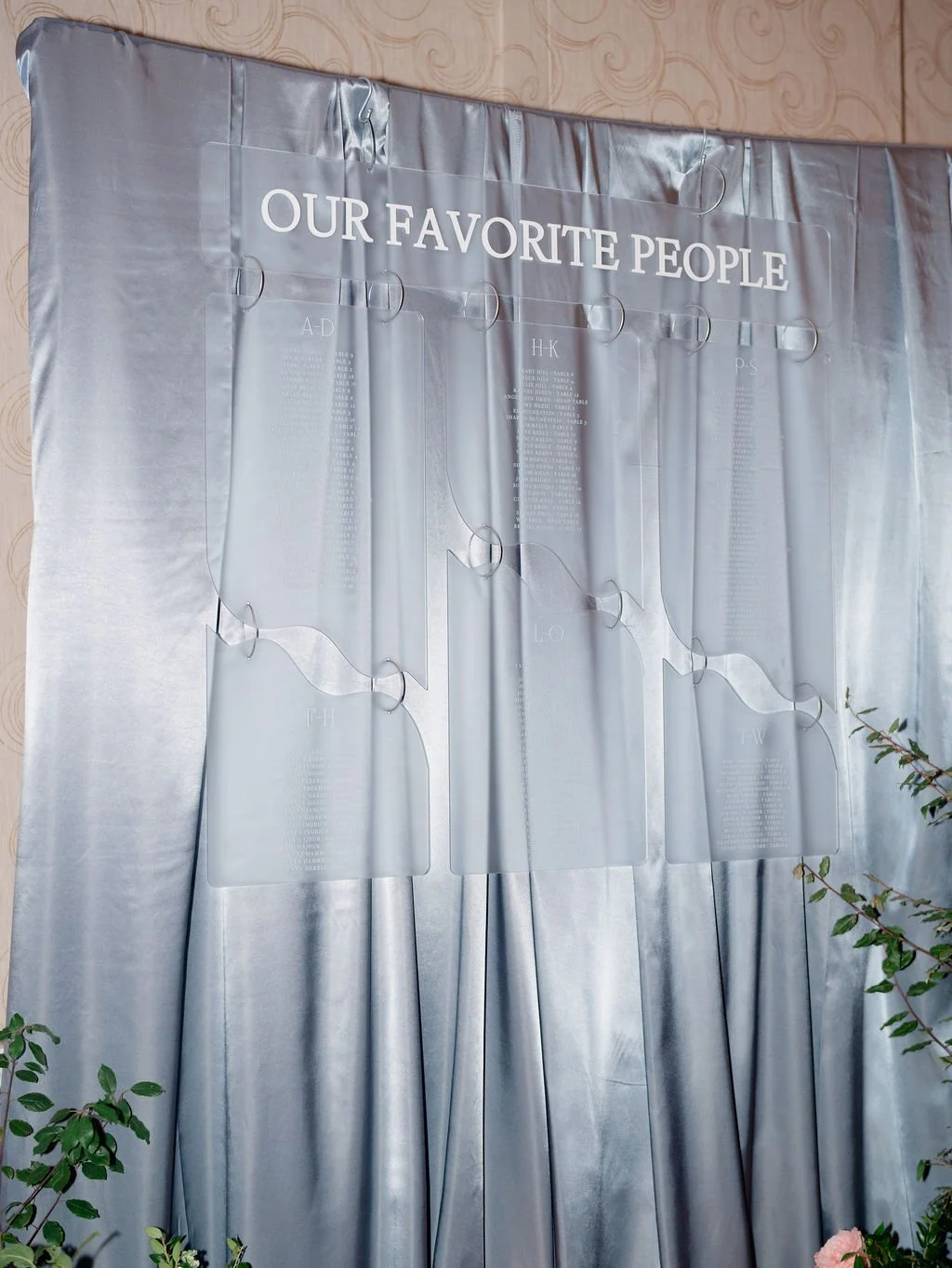 A large, shiny silver curtain with a transparent sign reading "Our Favorite People" hung above a list of names organized alphabetically by letter.