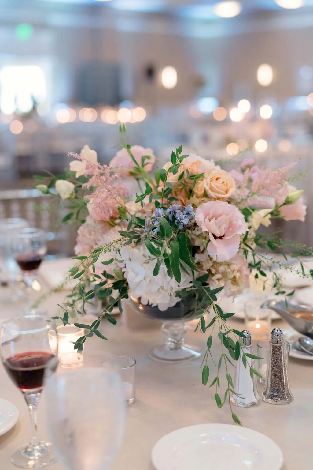 A table centerpiece with pink, white, and purple flowers in a vase at a banquet or wedding reception.