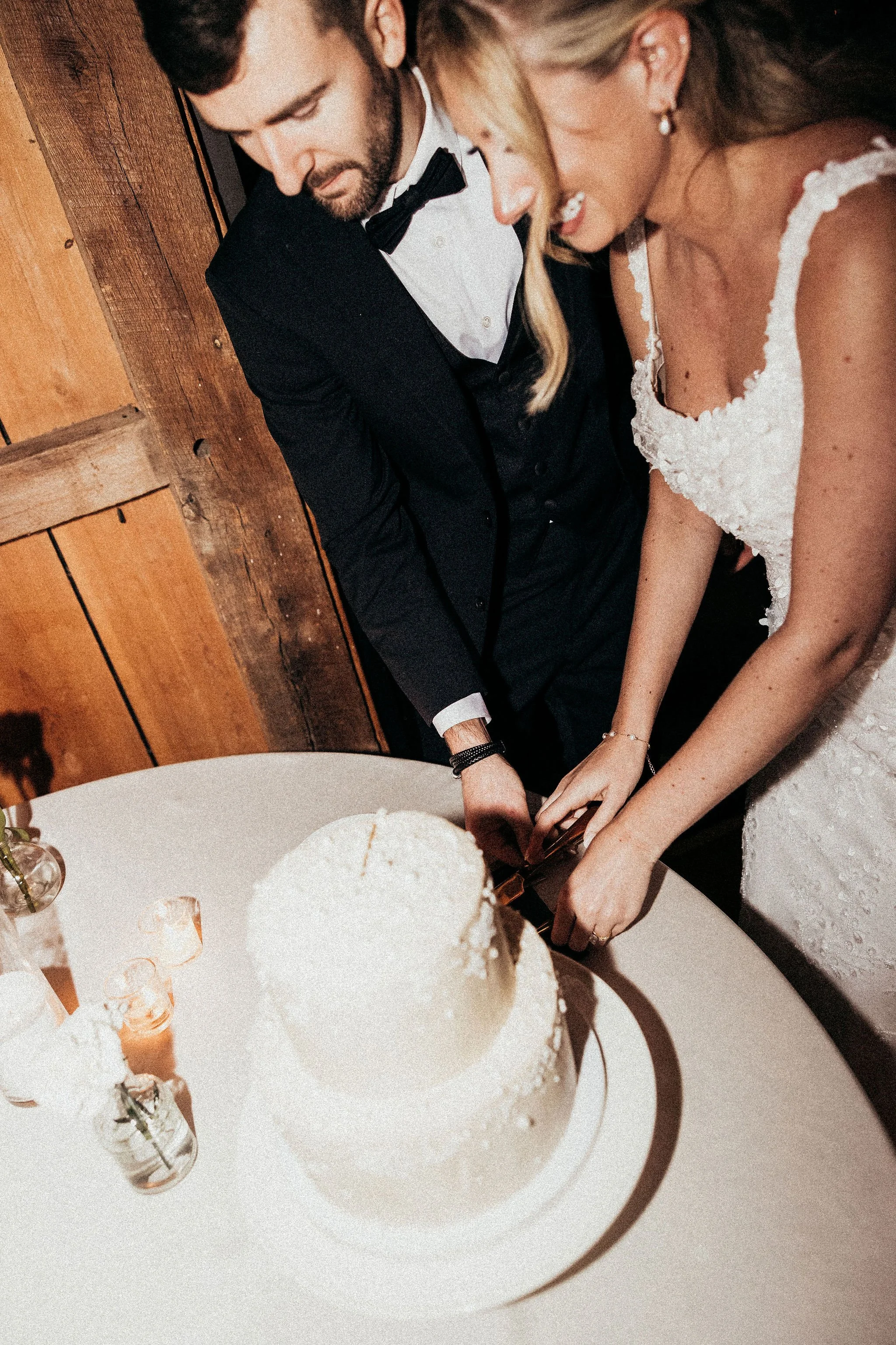 A bride and groom cutting a wedding cake together at their wedding reception.