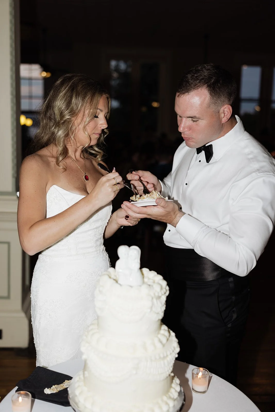 A bride and groom cutting cake at their wedding reception.