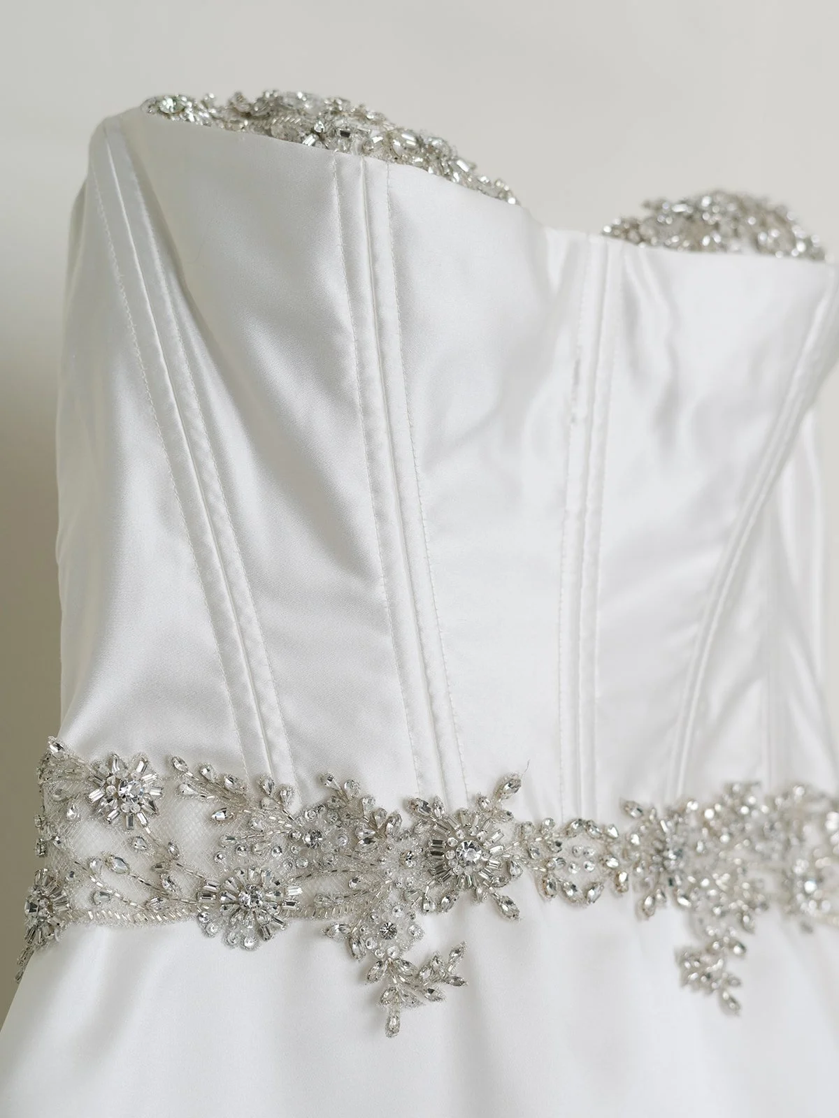 Close-up of a white wedding dress with decorative beading and embroidery on the bodice.