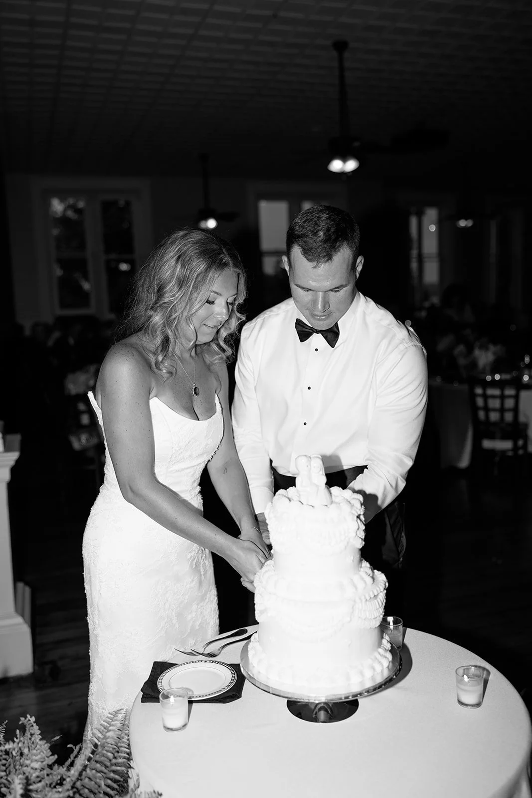 A bride and groom cutting a wedding cake together at their wedding reception.