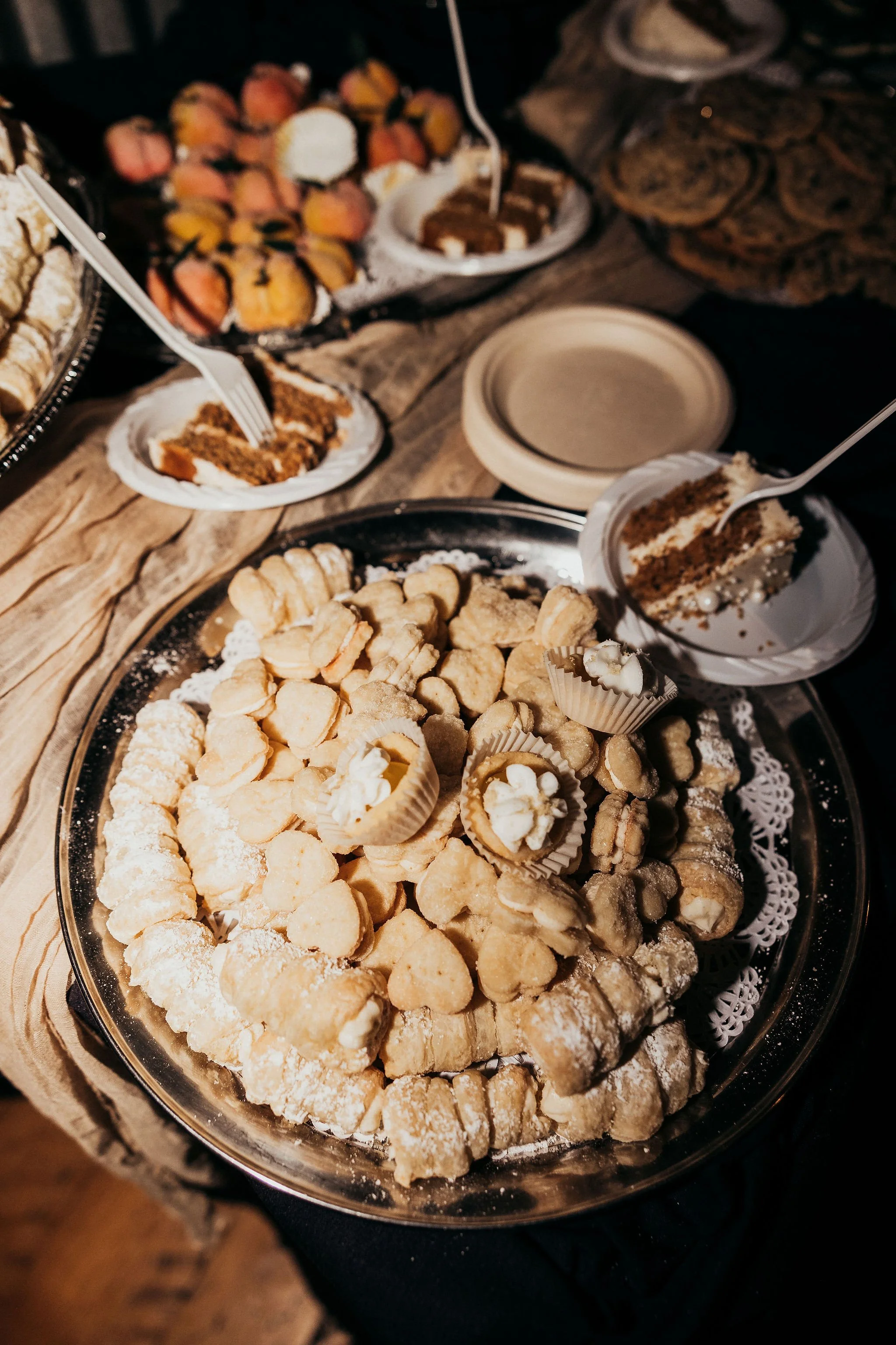 An assortment of desserts on a table, including cookies, cake slices, and pastries.
