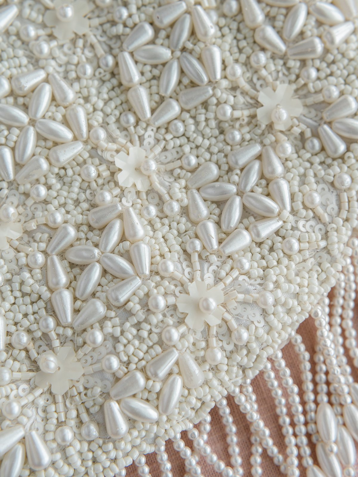 Close-up of white pearl and bead embellishments with floral designs on fabric.