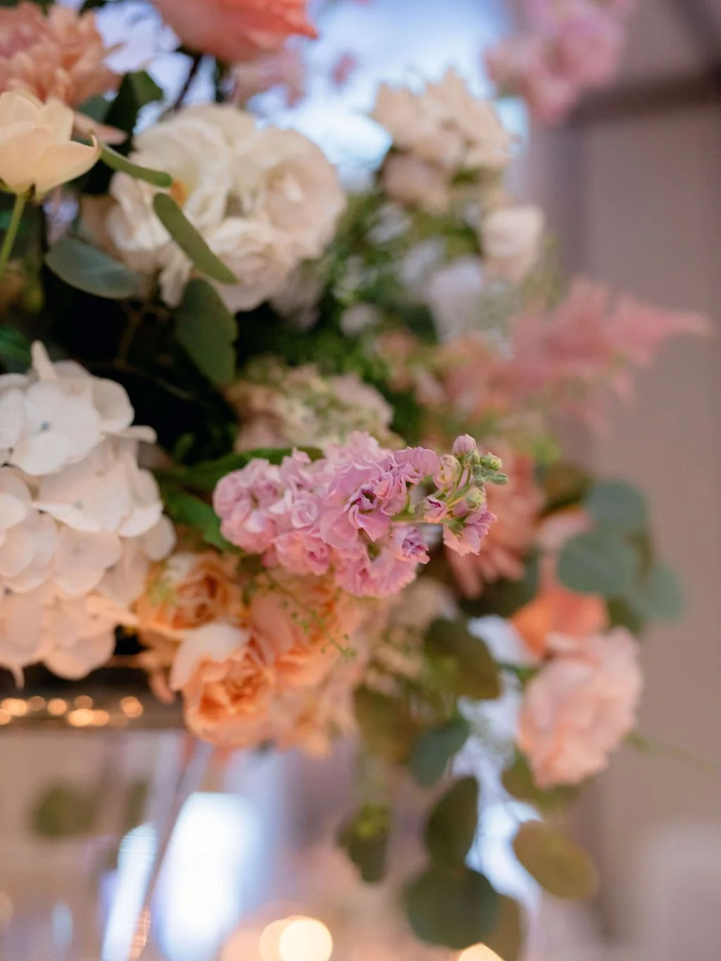 Close-up of a beautiful floral arrangement with pink, white, and peach-colored flowers and green leaves.