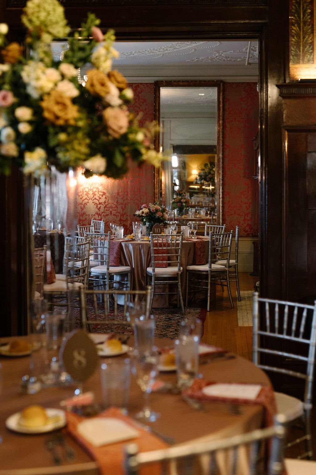 An elegantly set banquet table decorated with flowers in a historic or vintage-style dining room.