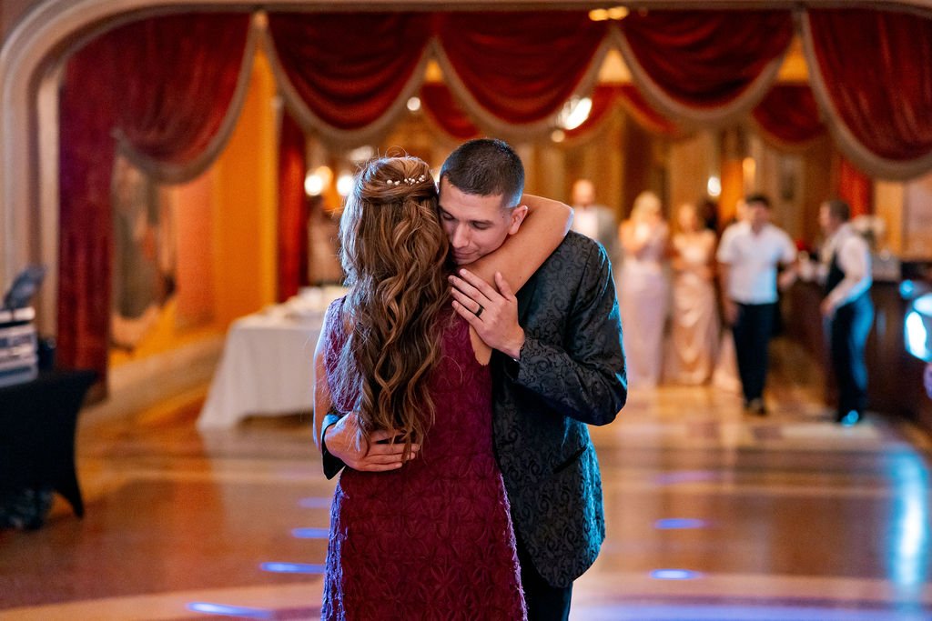 A young couple sharing a dance at a wedding reception in a decorated ballroom.