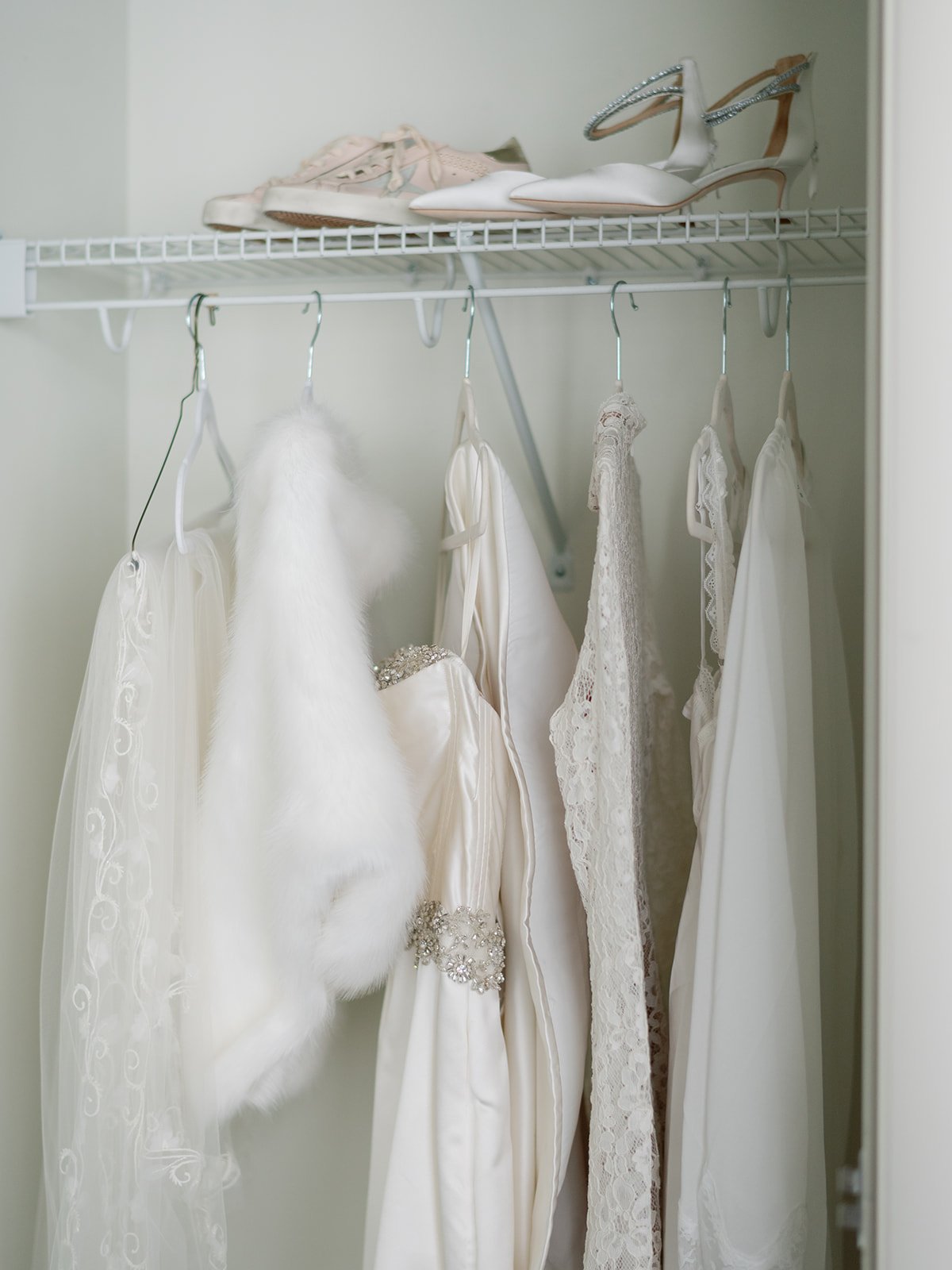 Wedding dress, veil, shoes, and accessories hanging in a wardrobe.