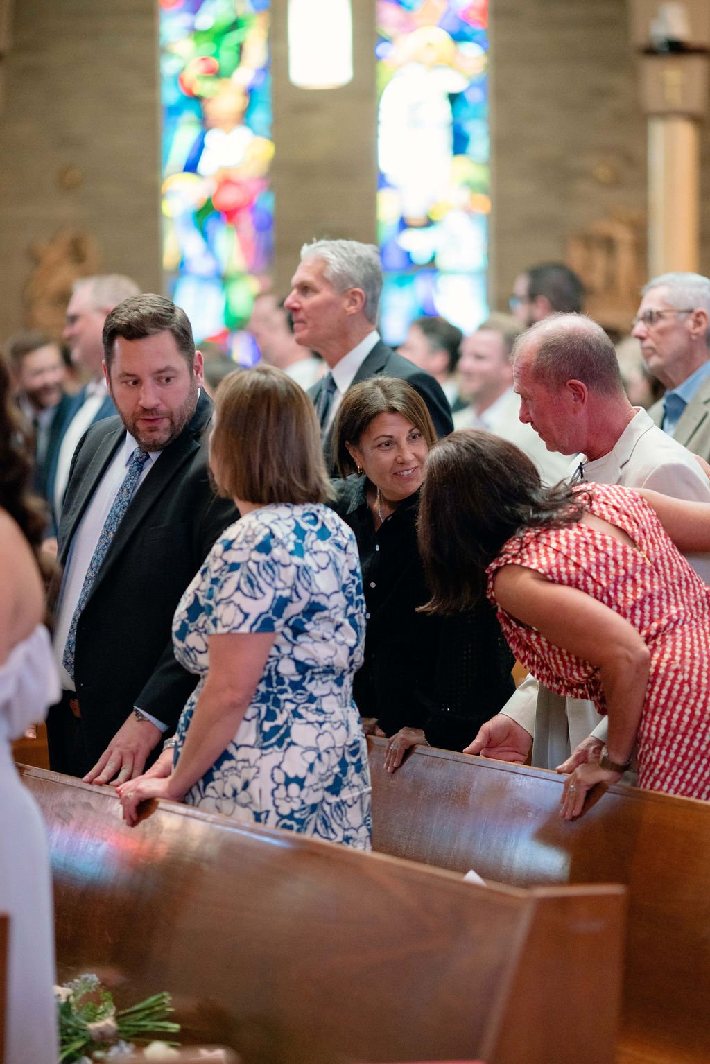 People gathered in church pews during a religious service inside a church with stained glass windows.