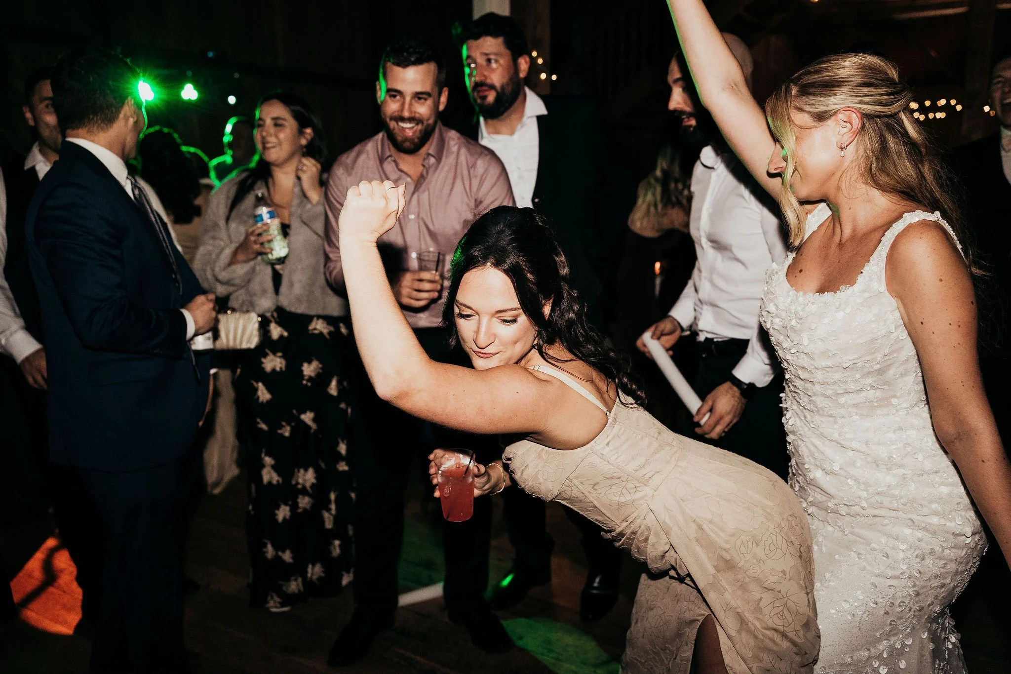 People dancing and enjoying themselves at a party or celebration, with some holding drinks and smiling.