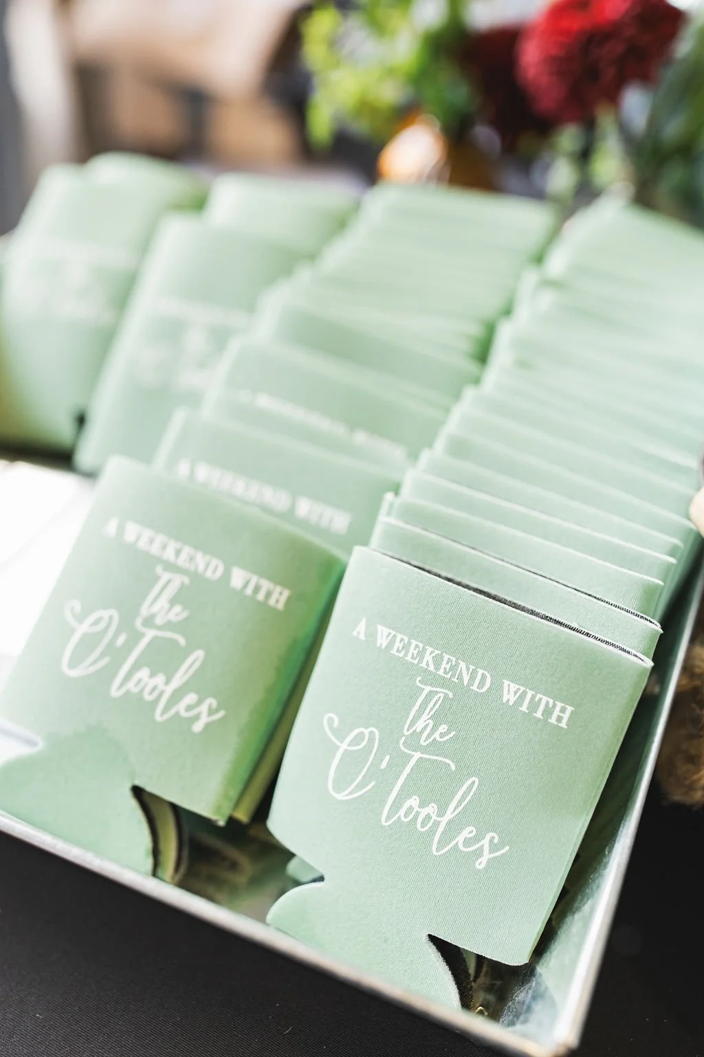 Multiple green cards with white cursive and block text that read "A Weekend with The Cools" are arranged in a display.