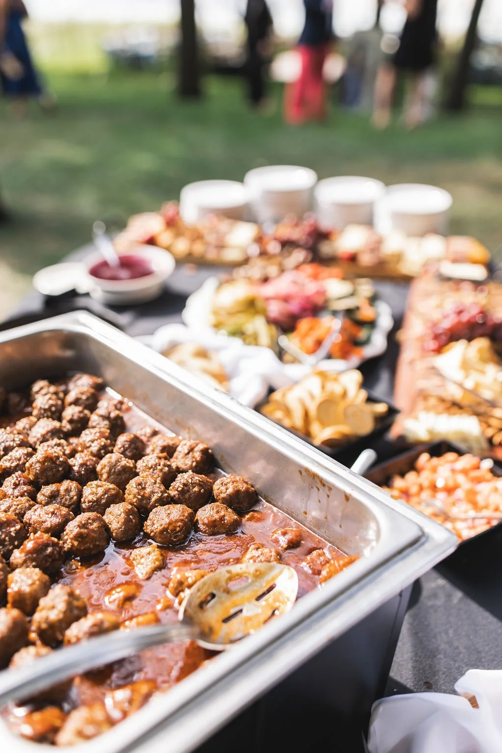Buffet table with meatballs and various dishes at an outdoor event.