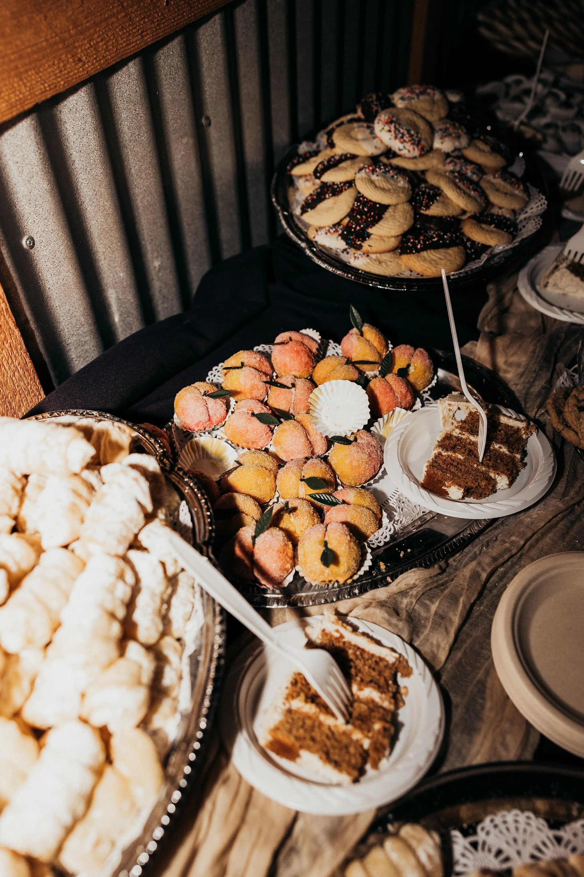 A dessert table featuring various baked goods, including cookies with colorful sprinkles, peach-shaped candies, and slices of cake.