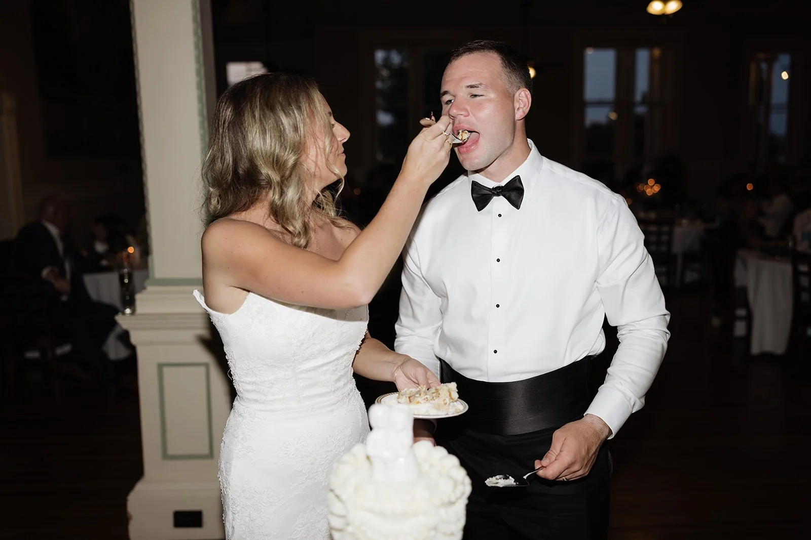 A bride feeding a groom cake at their wedding reception.
