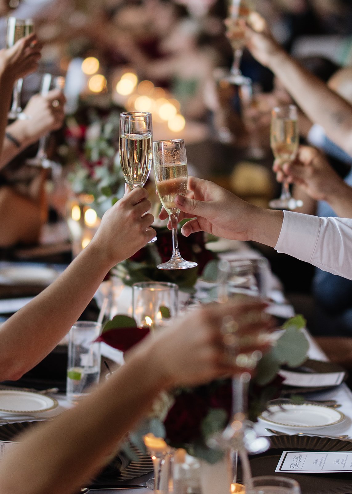 People raising champagne glasses in a toasting gesture at a formal dinner event.