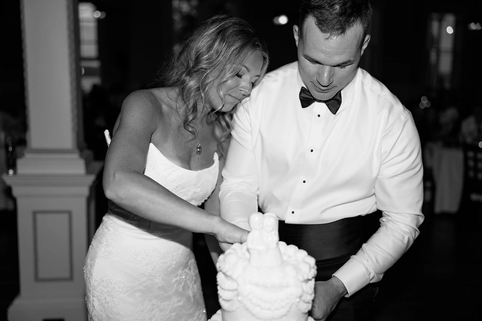 A bride and groom cut their wedding cake together at a wedding reception.
