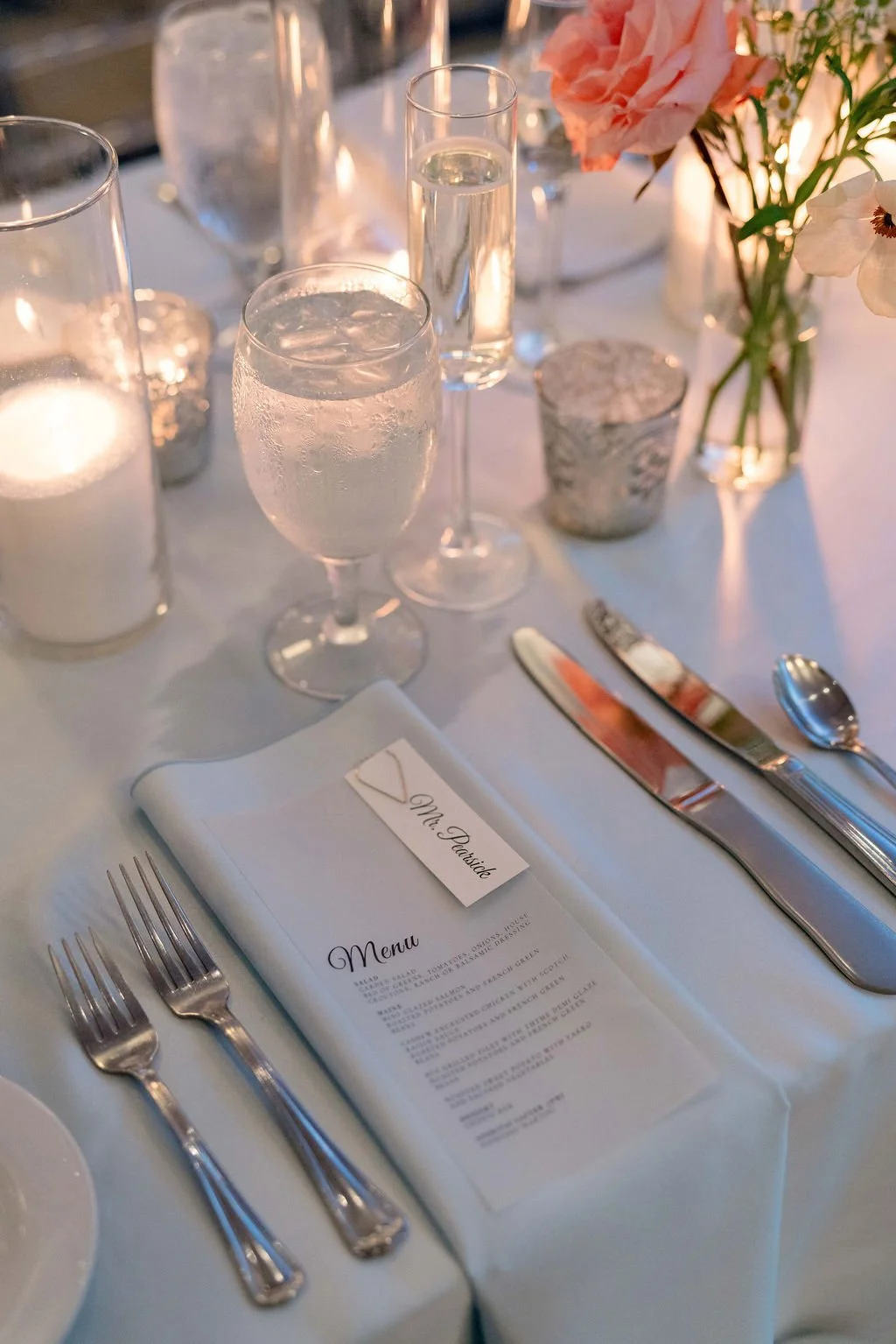 Elegant table setting with water glasses, a menu card, and floral centerpiece at a formal event.