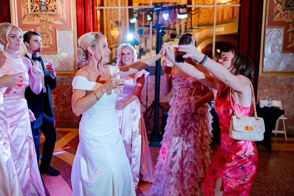 People dancing and celebrating at an elegant party or wedding reception in a decorated ballroom.