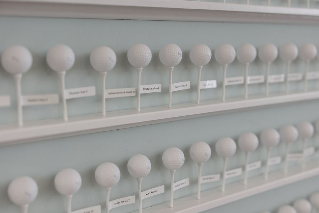 Display of white golf balls on a wall-mounted rack, each with a small label beneath.
