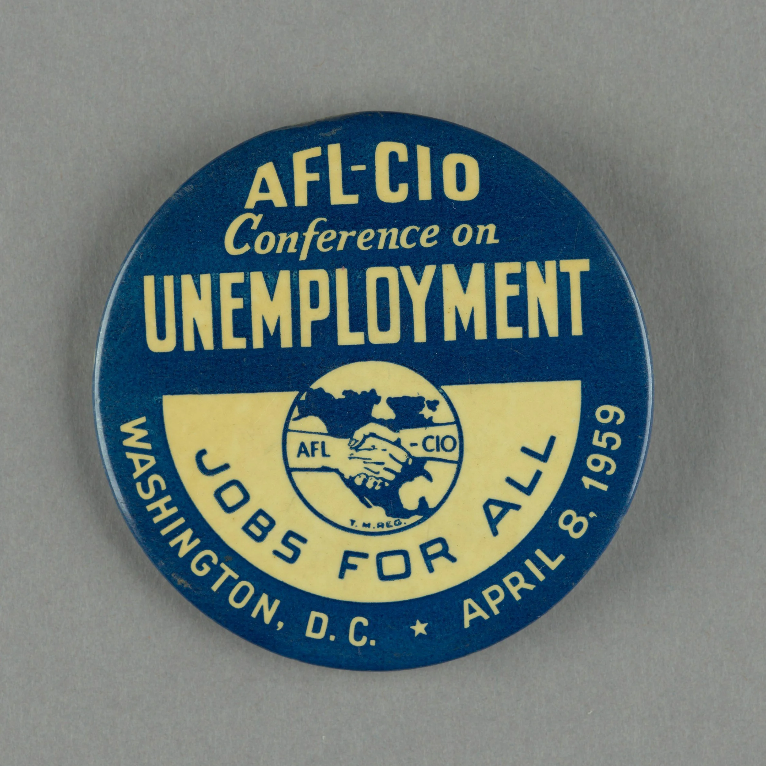 Close-up of a blue circular button with yellow text promoting the AFL-CIO conference on employment, featuring a globe graphic and additional organizational details.