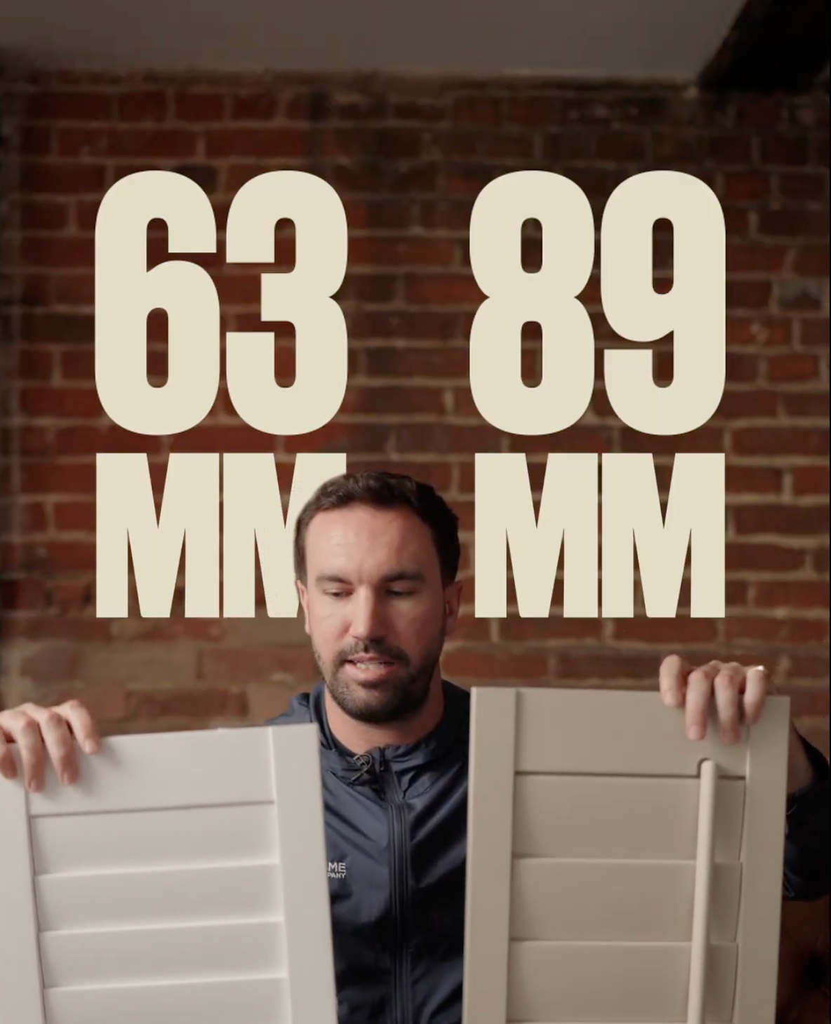 A man with a beard holds two white louvered panels, with large overlay text displaying time 63:89 and initials MM and MMM against a brick wall background.