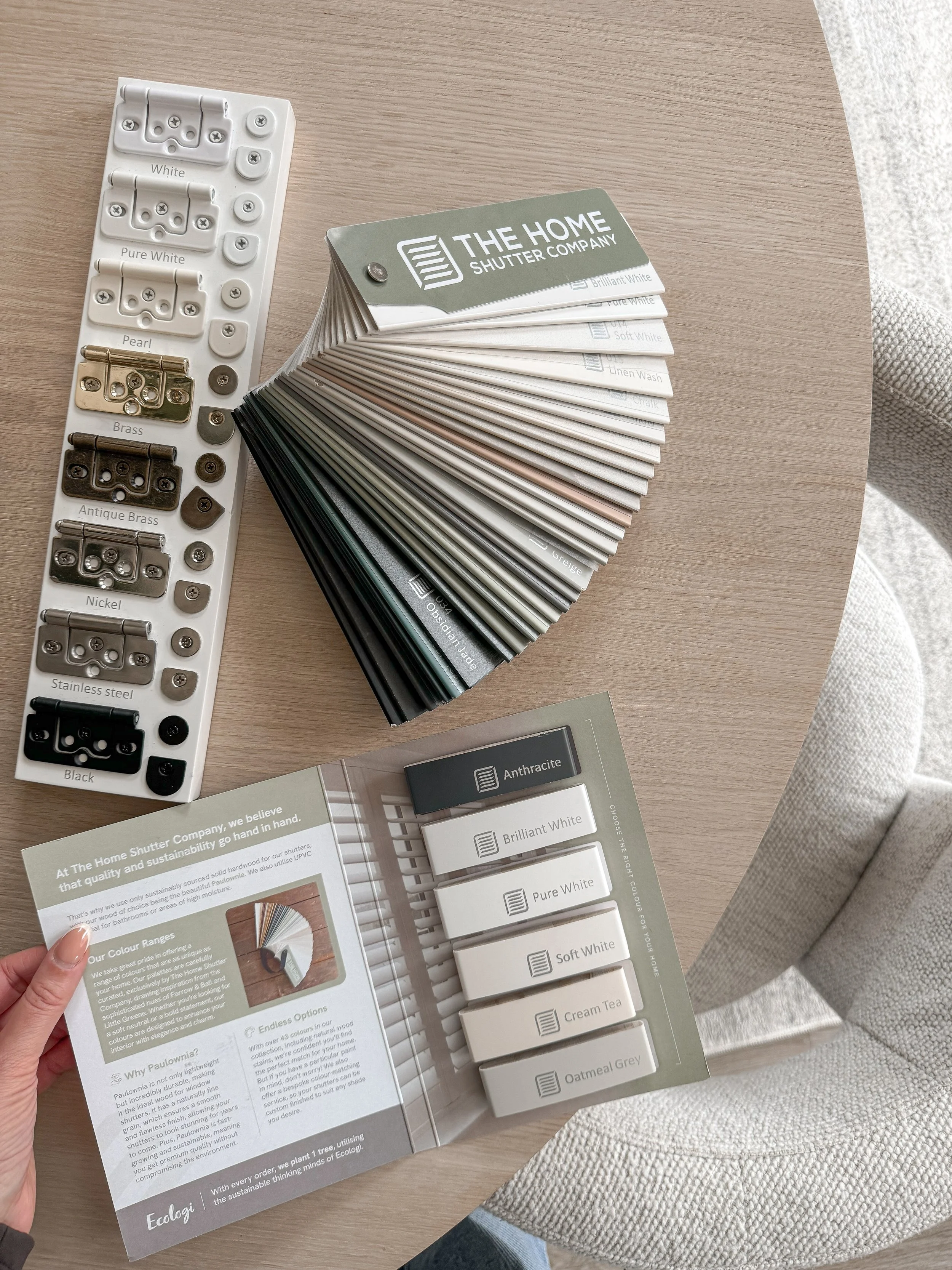 Color swatches and sample cards for different shades of white, cream, and gray for home shutters, along with brochures and a color catalog.