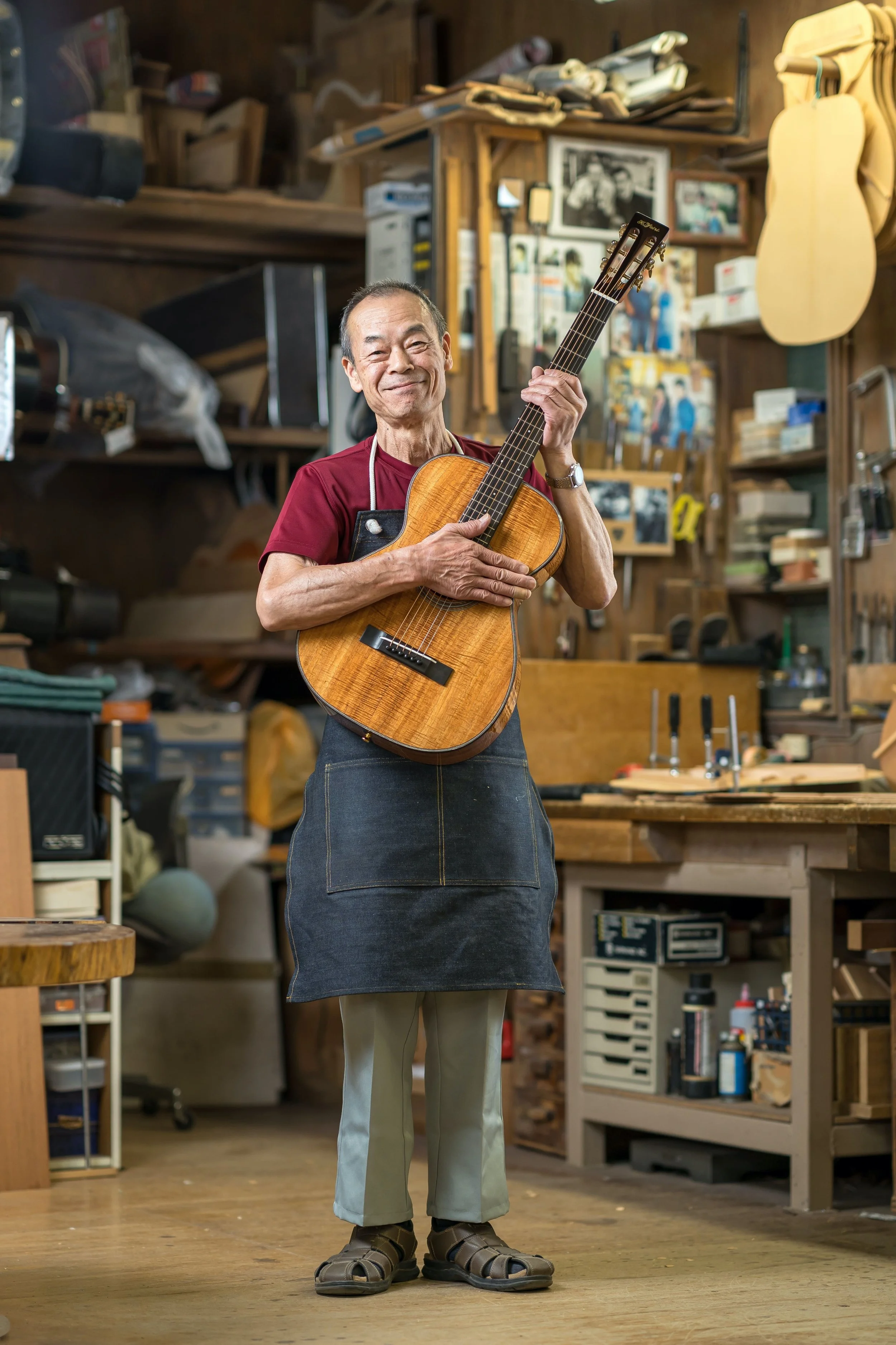 k yairi guitar manufacturer holding a guitar in the workshop in Japan