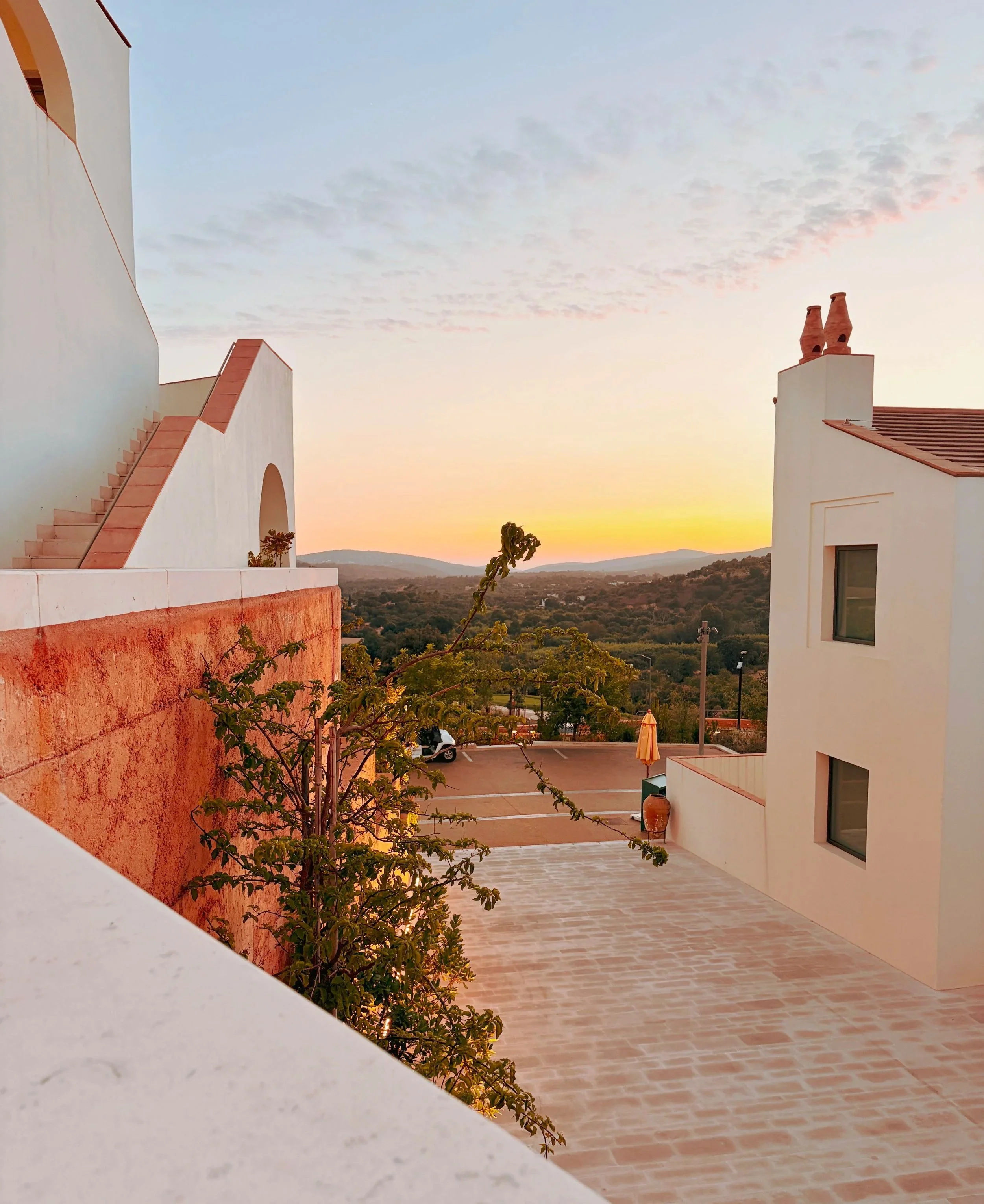 Scenic view of Viceroy at Ombria Algarve at sunset with greenery, and distant mountains.