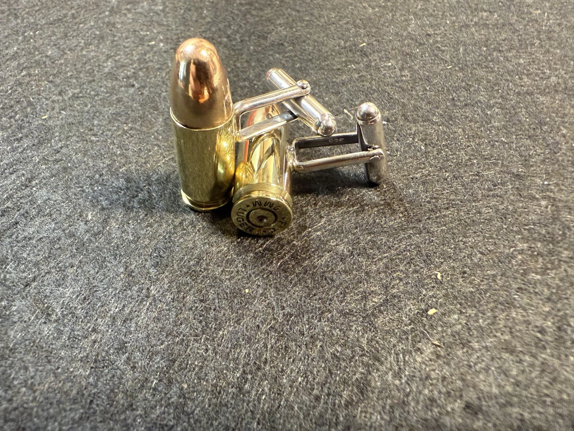 A set of 9mm cufflinks.
These are made by reseating a bullet in a once fired 9mm casing and then silver soldering sterling silver cufflink backs to them.  