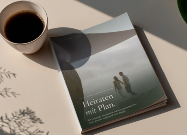 Eine Tasse schwarzen Kaffees und ein aufgeschlagenes Heiratsplaner-Buch auf einem hellen Tisch bei natürlichem Licht.