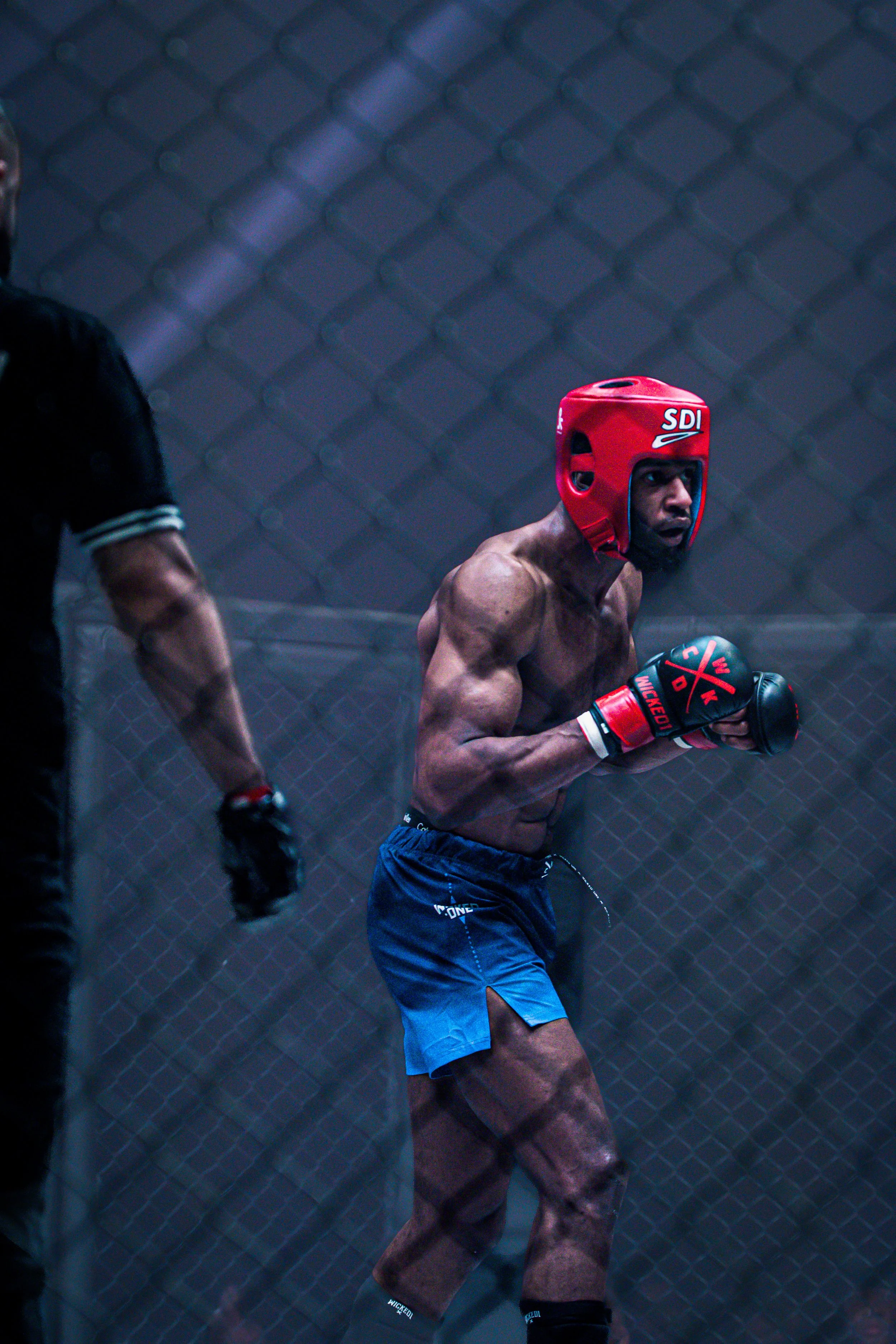 Photographie de Jacques Bonga, combattant de MMA à la Striker MMA League, en pleine action dans la cage, production visuelle réalisée par Lorraine Lemaire.